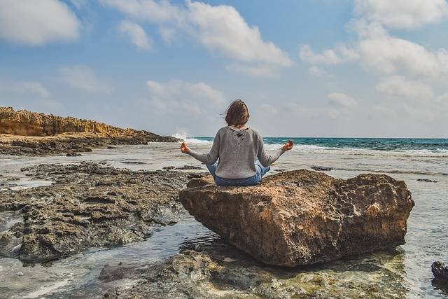 Personne sur un rocher en bord de mer qui profite de son temps libre grace aux revenues de sa location airbnb géré par Leenour conciergerie.